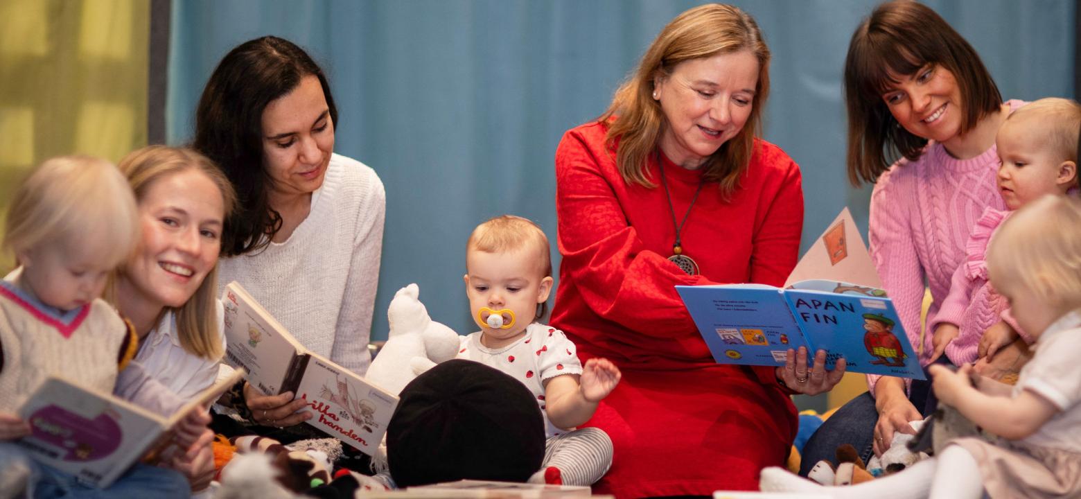 Småbarn med föräldrar och bibliotekarie som läser pekböcker för de små. 