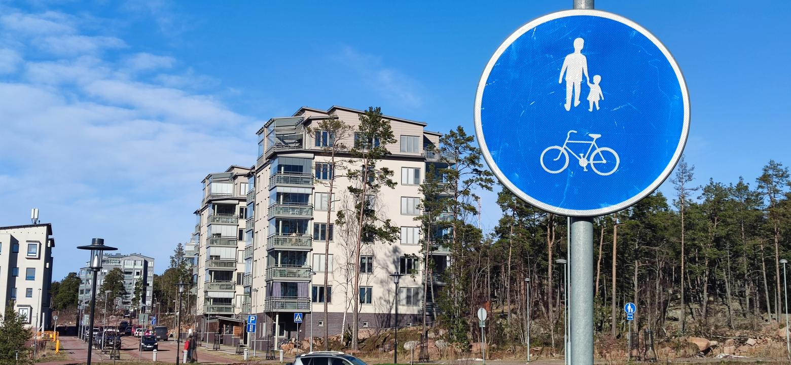 Gång- och cykelvägsskylt med höghus i bakgrunden